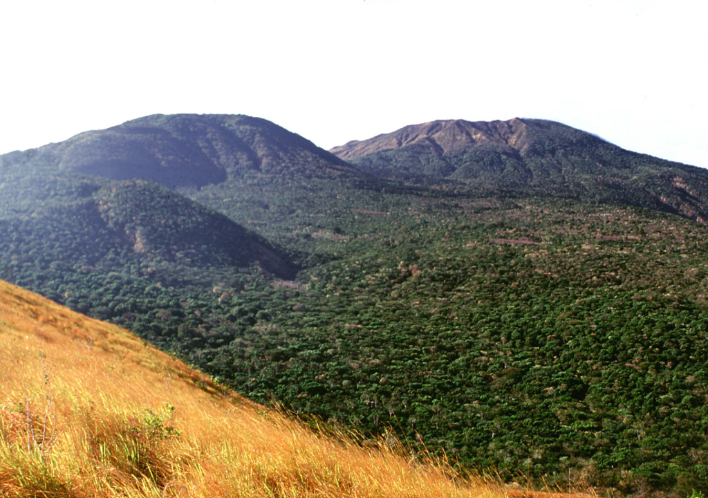 This view looking to the NW from Cerro Chino scoria cone shows some of the vents on the flank of Santa Ana, whose broad summit is to the right. The small vegetated cone in the midground to the left is Cerro el Astillero, and the larger cone behind it is Cerro Verde. Photo by Lee Siebert, 2002 (Smithsonian Institution).