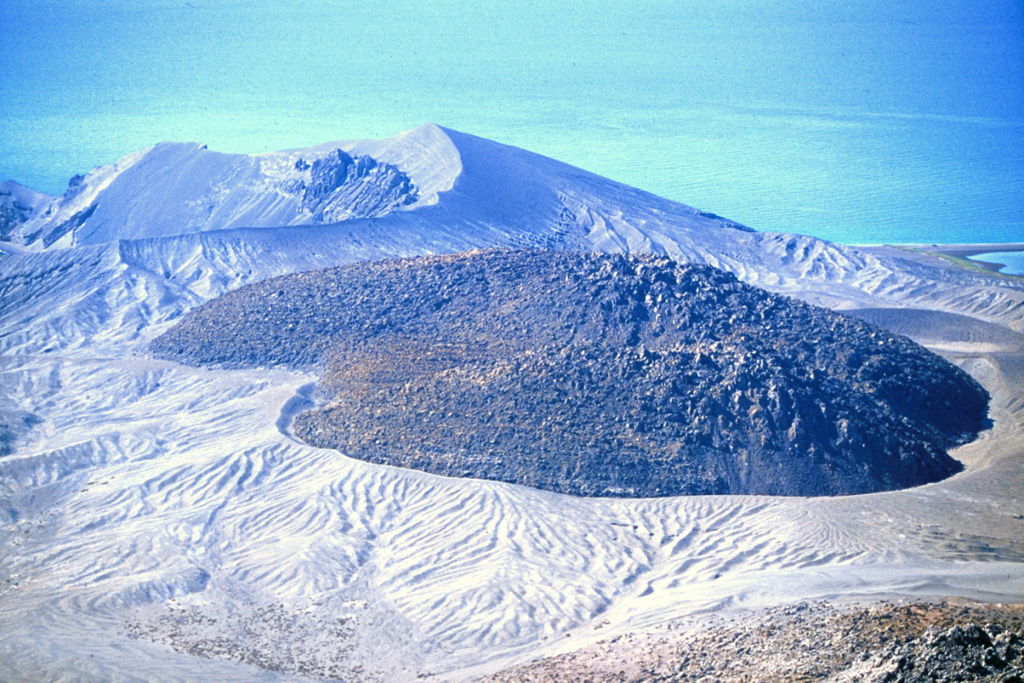 An obsidian lava dome fills the crater in the center of Isla San Luis, off the NE coast of Baja California, seen in this photo that was taken in 2000. As growth of the dome continued, a thick coulee advanced to the south and overflowed the rim to form the broad lobe behind it. The eroded Plaza de Toros tuff ring in the left background forms the SE tip of the island. Photo by Keith Sutter, 2000.