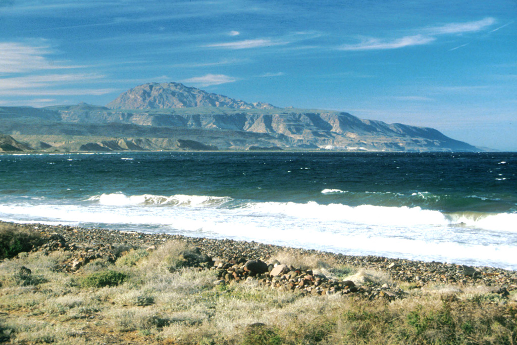 Post-caldera resurgent blocks of the early Pleistocene La Reforma caldera rise to the north above the Gulf of California.  The roughly 10-km-wide caldera contains a 1300-m-high central dome (left-center horizon) made of resurgent basement rocks.  Ignimbrite outflow sheets form flat surfaces and scarps, and uplifted marine terraces are prominent along the coast.  Photo by Brian Hausback, 1994 (California State University, Sacramento).