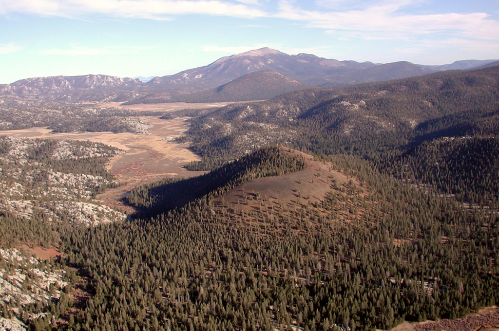 South Fork cinder cone (center) is seen from the NW with Ramshaw Meadow (upper left) behind it.  Templeton Mountain is the rounded peak beyond South Fork cone, and Olancha Peak on the crest of the Sierra Nevada is on the center horizon.  South Fork (Red Hill) cone was formed about 176,000 years ago and produced a lava flow 10 km to the west that may have reached as far as the Kern River.  The cinder cone was erupted through a bedrock ridge of the Sierra Nevada, and inclusions of quartz monzonite are common near the vents. Photo by Rick Howard, 2002 (courtesy of Del Hubbs, U S Forest Service).