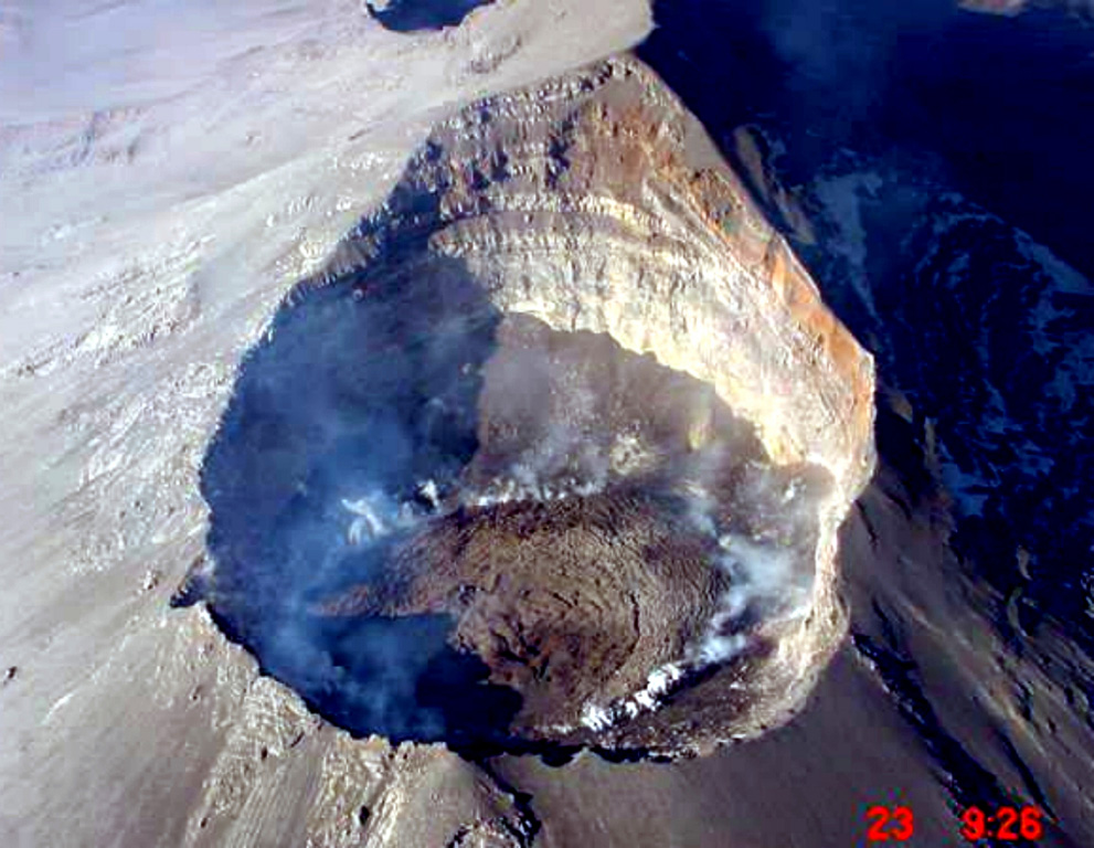 An aerial photograph from the NE on 23 December 2000 looks down into the Popocatépetl crater. Gas rises from the margins of lava emplaced in the summit crater since earlier that month. During December 2000 to January 2001 dome growth was at record-setting rates and amassed the largest active dome ever recorded at the volcano at the time. The previous dome-growth episode had taken place in February 2000.  Photo courtesy CENAPRED, Mexico City, 2000.