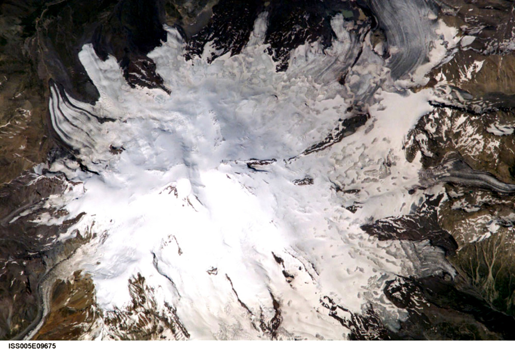 Mount Elbrus, the highest peak of the Caucasus Mountains of SW Russia, contains glaciers on its flanks. Elbrus has two summits separated by a low saddle. Snow-filled craters are visible in this image at both the eastern and western summits. Products of Mount Elbrus cover 260 km2 with its longest lava flow reaching 24 km down the NNE flank. Elbrus has been active into the Holocene. Weak fumarolic activity near the summit continues and hot springs are present on the flanks. Image courtesy of Earth Sciences and Image Analysis Laboratory, NASA Johnson Space Center, 2002 (http://eol.jsc.nasa.gov).