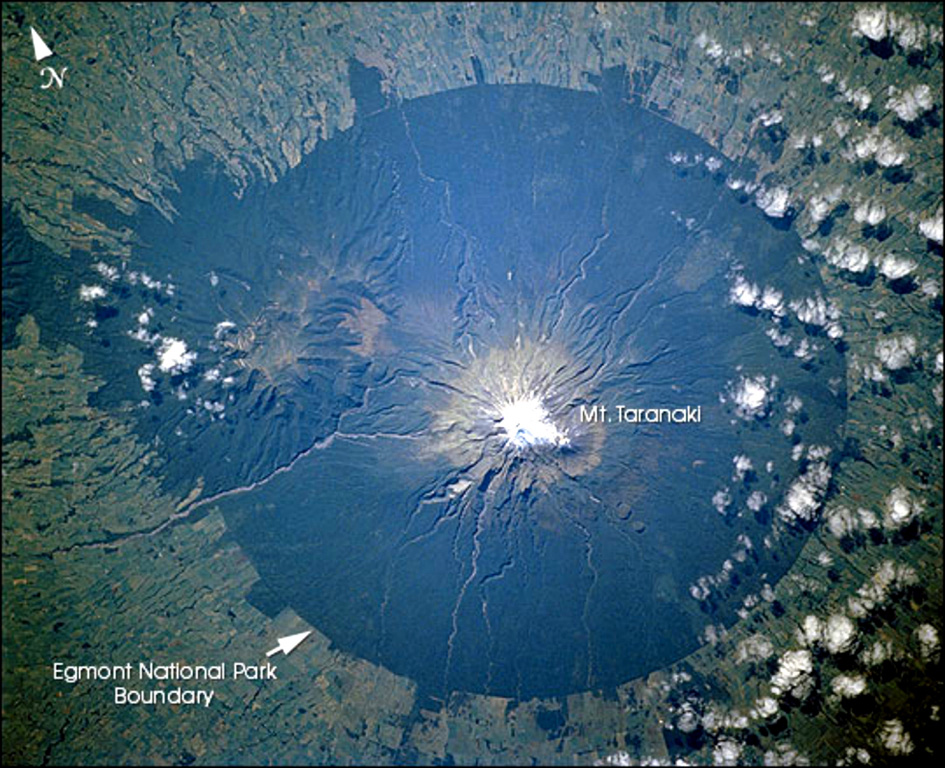 Mount Taranaki is the centerpiece of Egmont National Park on the W side of the North Island of New Zealand. Farmlands surrounding the volcano extend to the boundaries of the national park, leaving a circular pattern prominent from space. The Pleistocene Kaitoke Range forms the topographic high to the WNW. NASA Space Shuttle image STS110-726-6, 2002 (http://eol.jsc.nasa.gov/).