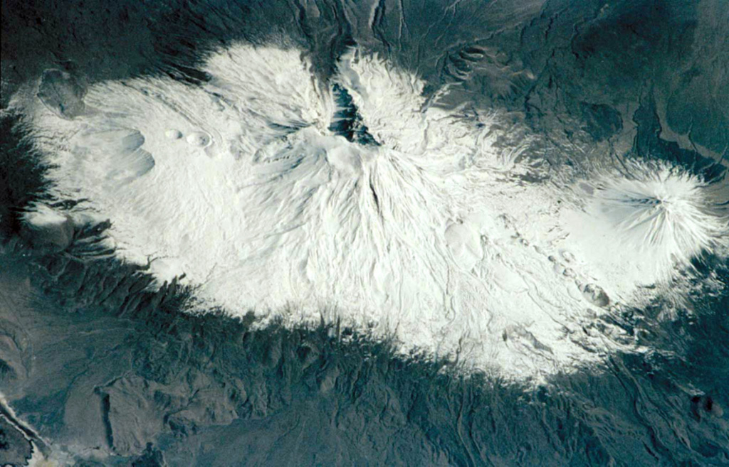 This Space Shuttle image shows the massive 1,000 km3 snow-capped Ararat massif in March 2001. The N-trending feature descending at the top-center from the summit crater is Ahora Gorge. The conical peak of Kucuk Ararat (Lesser Ararat) is visible at the far right, and craters can be seen on the western flank of the massif at the left. Image courtesy of Earth Sciences and Image Analysis Laboratory, NASA Johnson Space Center, 2001 (http://eol.jsc.nasa.gov).
