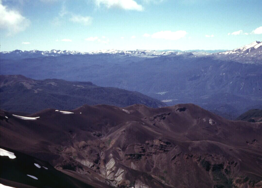 The snow-capped Cordón Caulle volcanic massif rises on the left horizon across the Río Gol Gol valley from the Antillanca volcano group in the foreground.  The Cordón Caulle is a group of post-caldera silicic vents formed along a 17-km-long, 2.5-km-wide WNW-ESE rift zone extending to the SE towards Puyehue volcano, whose flanks form the far right horizon.  Historical eruptions have occurred from several points along the Cordón Caulle fissure system during the 19th and 20th centuries.     Photo by Klaus Dorsch, 2001 (University of Munich).