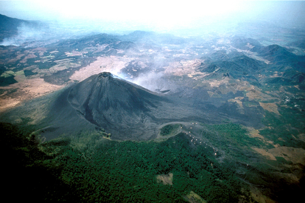 An aerial view from the NNW shows gas emanating from the MacKenney cone. The rim of the large horseshoe-shaped crater within which the cone was constructed is visible in the foreground, partially covered by Cerro Chino scoria cone on the right. The crater formed by collapse of Pacaya during the late-Holocene and produced a debris avalanche that traveled down the Metapa river drainage to the SE, reaching as far as the Pacific coastal plain 25 km away. Copyrighted photo by Stephen and Donna O'Meara, 1999.