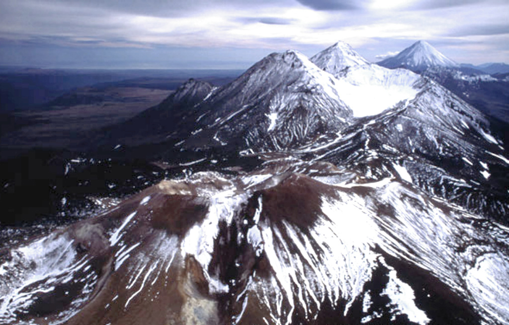 The Komarov volcanic complex is seen in the foreground in this view from the north toward the Gamchen volcanic range. Komarov, the youngest cone, was built at the western end of a 2.5 x 4 km caldera. It has craters, one at the summit and the other on the upper east flank. The Gamchen massif beyond Komarov consists of three Late-Pleistocene and one Holocene cones. Kronotsky is seen on the far-right horizon. Copyrighted photo by Philippe Bourseiller (Holocene Kamchataka volcanoes; http://www.kscnet.ru/ivs/volcanoes/holocene/main/main.htm).