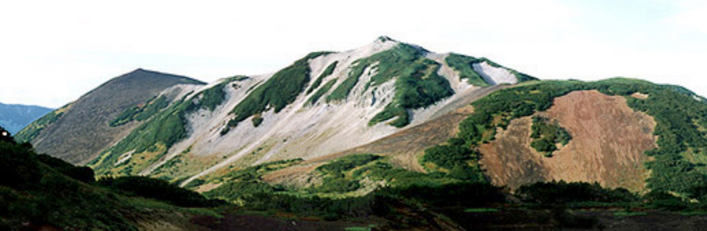 The Holocene scoria cones of Barkhatnaya Sopka are located on a plateau 13 km N of Vilyuchik volcano on an uplifted eroded Miocene-Pliocene block. In this view looking NE, the Mt. Barkhatnaya cone which formed 3,000-4,000 years ago is to the left, and the reddish hill to the right is an early Holocene scoria cone. The white hill in the center is a part of an eroded rhyolitic body. Coyrighted photo by Oleg Dirksen (Holocene Kamchataka volcanoes; http://www.kscnet.ru/ivs/volcanoes/holocene/main/main.htm).