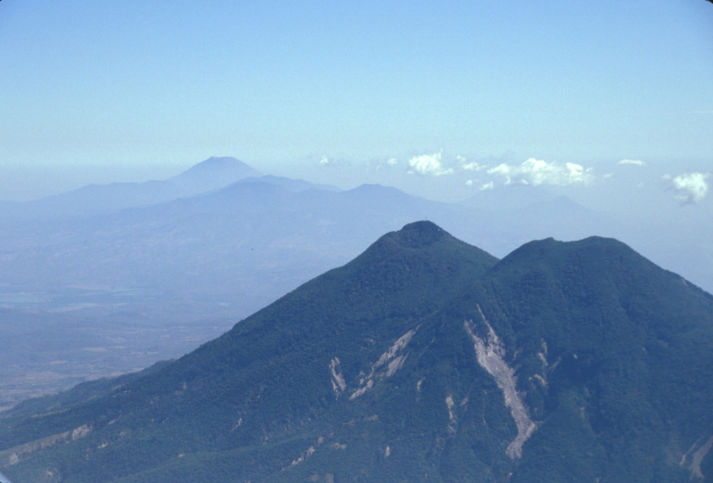 San Vicente is seen here in 2002 with landslide scarps that were produced during the January 2001 earthquake. The San Vicente area and towns at the base of the volcano were particularly affected by the tectonic earthquake and suffered extensive damage. The Tecapa volcanic complex and conical San Miguel volcano are in the distance. Photo by Paul Kimberly, 2002 (Smithsonian Institution).