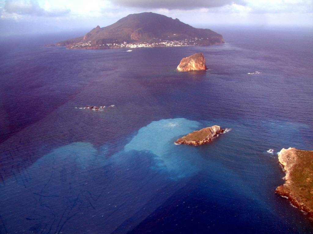 Panarea Island is the largest subaerial component of a mostly submarine volcanic complex between Lipari and Stromboli volcanoes. The last eruptions took place during the early Holocene, but hydrothermal activity has continued at fumarolic fields at several locations on the submerged platform. The water discoloration in the foreground, 2 km E of Panarea Island, near the small islands took place during November 2002. Photo courtesy of Istituto Nazionale di Geofisica e Vulcanologia, Sezione di Catania (INGV), 2002.