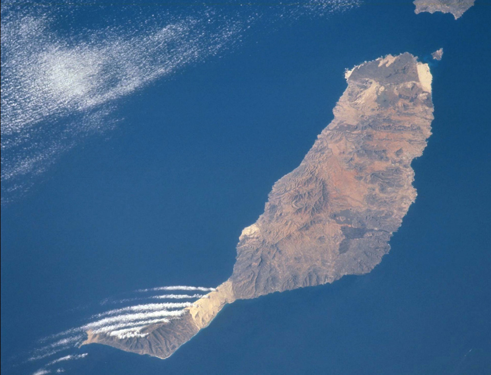 Pleistocene and Holocene cinder cones and lava flows cover large portions of Fuerteventura Island at the eastern end of the Canary Islands. As seen in this image taken from the International Space Station, the youngest lavas form the darker colored areas at the northern tip of the island, including the small Isla de Lobos off the tip of Fuerteventura, as well as in the south-central part of the arid island. The linear clouds off the southwest are not related to volcanic activity. NASA International Space Station image ISS002-732-26, 2001 (http://eol.jsc.nasa.gov/).
