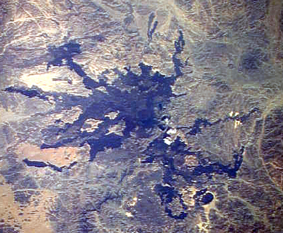 Lava flows radiate down desert valleys away from the center of Harrat Lunayyir, a basaltic volcanic field in NW Saudi Arabia, east of the Red Sea port of Umm Lajj. Harrat Lunayyir contains about 50 volcanic cones that were constructed along a N-S axis. Harrat Lunayyir is one of the smallest of the Holocene lava fields of Saudi Arabia, but individual flow lobes extend up to about 30 km from the center of the Harrat. One of the cones may have erupted around the 10th century CE or earlier. NASA Space Shuttle image STS26-41-61, 1988 (http://eol.jsc.nasa.gov/).