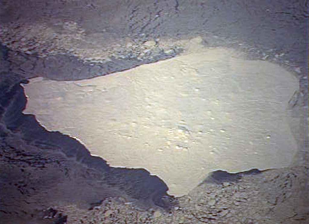 Low-angle sun accentuates small pyroclastic cones on snow-covered Nunivak Island.  Shelf ice modifies the apparent northern coastline (top) in this January 1992 Space Shuttle image.  The 110-km-wide island lies about 30 km off the coast of SW Alaska and contains about 60 cinder cones and four maars.  Although the bulk of the volcanic field was formed during two Pleistocene eruptive periods ending about 300,000 years ago, activity continued into the Holocene.  The latest eruptions occurred along an E-W line in the southern part of the island. NASA Space Shuttle image STS42-82-33, 1992 (http://eol.jsc.nasa.gov/).
