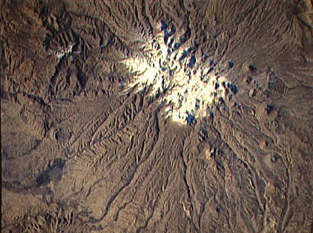 Sahand volcano (Kuh-e-Sahand) is located in NW Iran, about 60 km E of Lake Urmia and 40 km SSE of the city of Tabriz. The city of Maragheh (darker area at bottom left) lies below the S flanks of the volcano. Numerous lava domes (upper right) occupy the lower flanks of the volcano. NASA Space Shuttle image STS74-708-25, 1995 (http://eol.jsc.nasa.gov/).