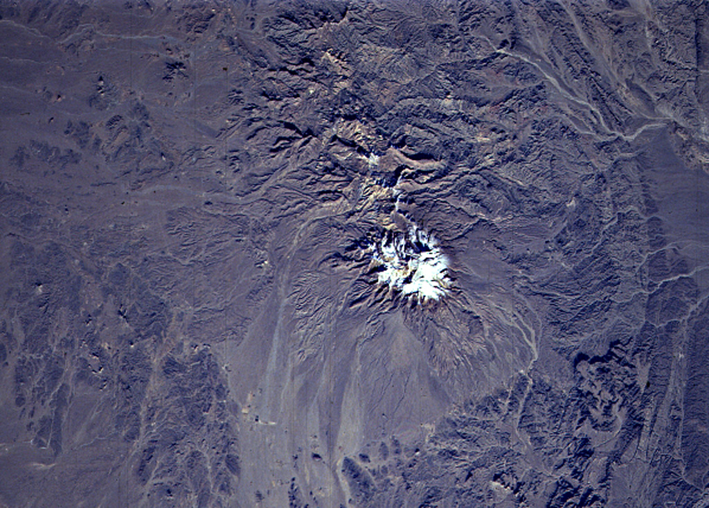 The snow-capped, eroded Taftan volcano in eastern Iran has two prominent summits. It was constructed along a volcanic zone in Beluchistan, SE Iran, that extends into northern Pakistan. The higher SE summit cone is well preserved and has been the source of very visible lava flows. Highly active, sulfur-coated fumaroles occur at the summit of the SE cone. NASA Space Shuttle image STS80-752-40, 1996 (http://eol.jsc.nasa.gov/).
