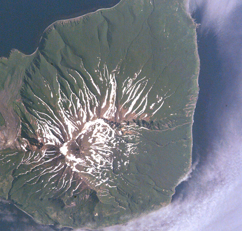 Milne, the southernmost volcano on Simushir Island, lies immediately SE of Goriaschaia volcano (far left) in this Space Shuttle image (N is to the upper left). The walls of a 3-km-wide Pleistocene crater that opens towards the sea are visible in the lower half of the image. The small, mostly snow-free central cone near the crater headwall contains a lava dome that was constructed during postglacial time and forms the highest point on the island. NASA International Space Station image ISS005-E-6511, 2002 (http://eol.jsc.nasa.gov/).