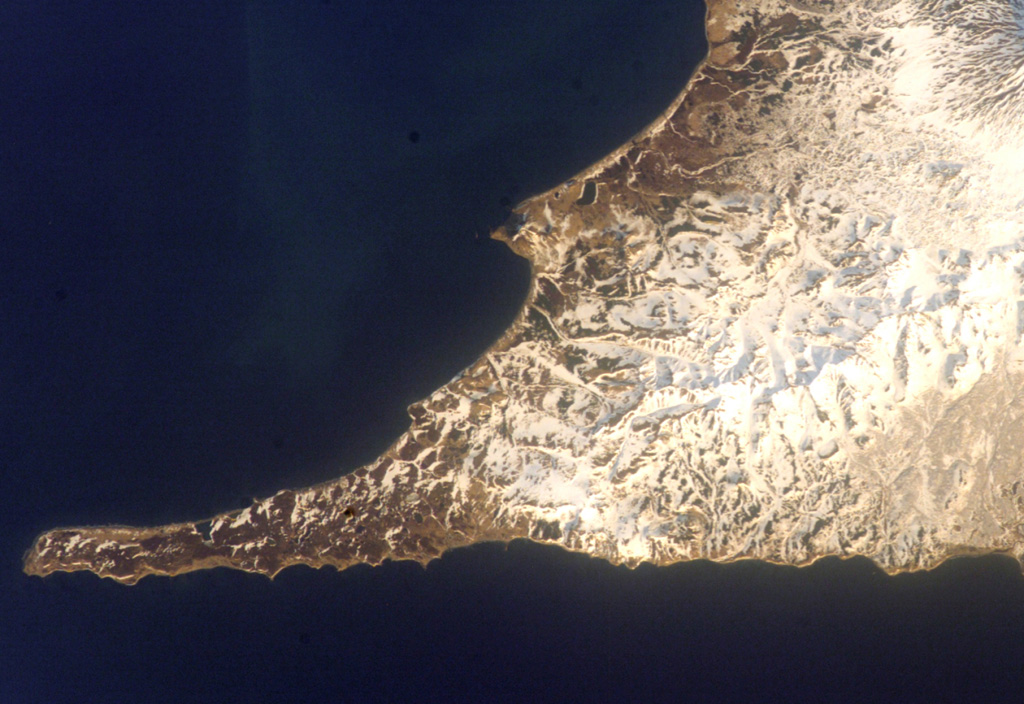 The small peninsula extending into the Sea of Okhotsk just above the center of the image is Mashkovtsev, the southernmost young volcano of Kamchatka.  Cape Lopatka, the southern tip of Kamchatka, lies at the end of the narrow SW-pointing peninsula at the lower right in this International Space Station image with the Pacific Ocean at the bottom.  Mashkovstev is a small basaltic stratovolcano that has a postglacial summit cone.  Two small basaltic cones are located to the north. NASA International Space Station image ISS004-E-11698, 2002 (http://eol.jsc.nasa.gov/).