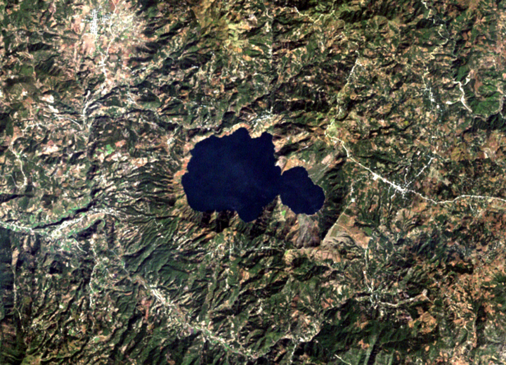 One of the most prominent topographic features of SE Guatemala is the figure-8-shaped double caldera of Ayarza volcano.  Both calderas were formed within several thousand years of each other during major rhyolitic explosive eruptions in the late Pleistocene, about 27,000 years ago (eastern caldera) and 23,000 years ago (the larger western caldera).  Formation of the older caldera was accompanied by the eruption of the chemically mixed pumices of the "Mixta" unit.  The city of San Rafael las Flores, 6 km to the NE, is at the upper left.   NASA Landsat image, 2000 (courtesy of Loren Siebert, University of Akron).