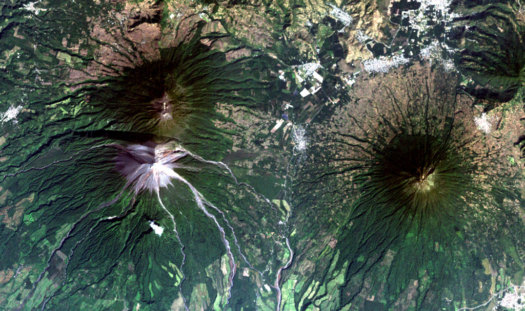 The historical city of Antigua Guatemala (top-right margin) is surrounded by three major stratovolcanoes in this Landsat view with north to the upper right.  Dark-colored Acatenango volcano (upper left) and the unvegetated summit of Fuego volcano lie SW of the city, and Agua volcano (right-center) lies south.  No historical eruptions from Agua are known, although mudflows in 1541 caused the abandonment of Ciudad Vieja, the previous capital city of Guatemala.  Barrancas radiating SE from Fuego are light-colored from deposits of historical eruptions.  NASA Landsat image, 2000 (courtesy of Loren Siebert, University of Akron).