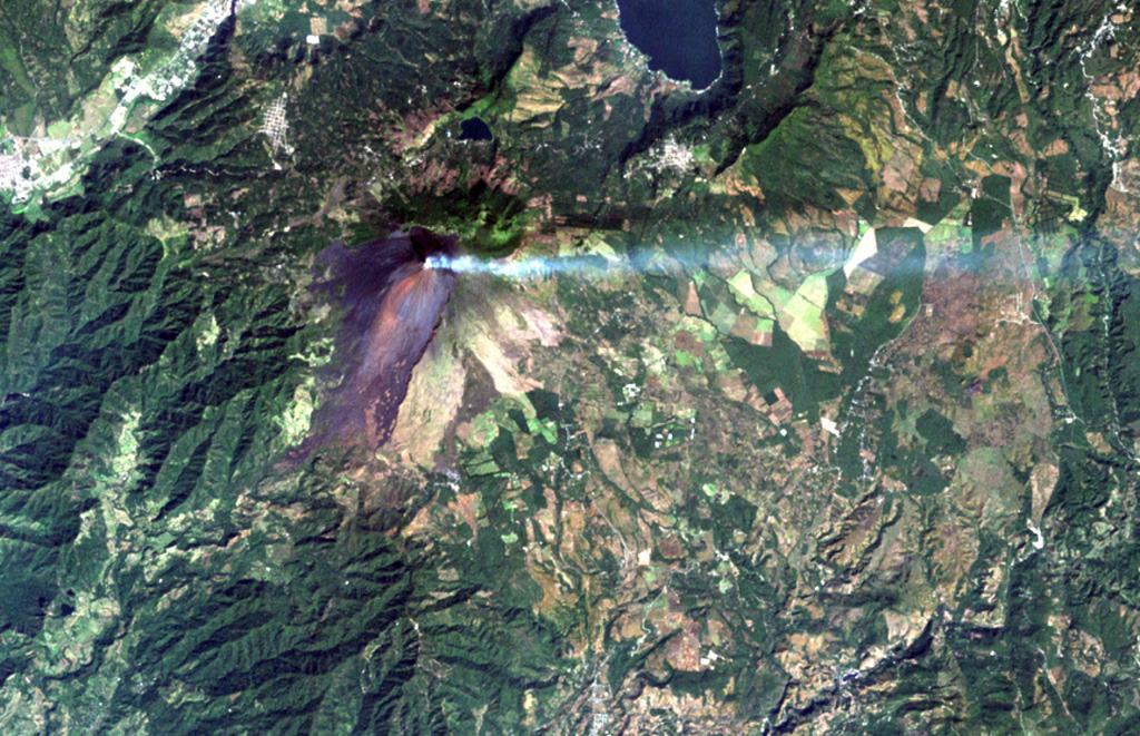 A volcanic plume extends to the east from MacKenney crater at Pacaya volcano in this December 8, 2000 Landsat image.  The unvegetated modern cone was constructed within a scarp (visible south of the summit) left by a major edifice collapse at Pacaya volcano about 1100 years ago.  The avalanche swept 25 km down the Río Metapa drainage (lower left) to the Pacific coastal plain.  Pacaya was constructed near the southern rim of Amatitlán caldera, partially filled by Lake Amatitlán at the top right. NASA Landsat image, 2000 (courtesy of Loren Siebert, University of Akron).