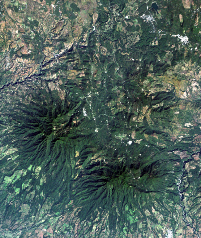 The top-center portion of this Landsat image consists of topographically indistinct Piedra Grande, a cluster of faulted, heavily eroded andesitic stratovolcanoes.  The Piedra Grande complex lies between the NW-trending Jalpatagua Fault, which cuts diagonally through the city of Barbarena (the small white area at the upper right), and Tecuamburro volcano (lower right).  The vent area of Piedra Grande lies within 4-km-wide, nested depressions open to the east, NE of the more prominent forested Puebla Nuevo Viñas volcano (left center).    NASA Landsat image, 2000 (courtesy of Loren Siebert, University of Akron).