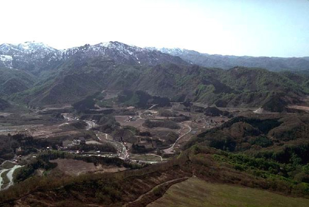 Hijiori volcano, seen from the E, is a small caldera located NE of the Pleistocene Gassan volcano. The town of Hijiori lies in the left foreground along the banks of two rivers through the caldera floor. The low 2.5-km-wide caldera formed during a large eruption between about 9,500 and 11,000 years ago, accompanied by pyroclastic flows and ashfall that extended to the E and reached the Pacific coast. Copyrighted photo by Hiroshi Yagi (Japanese Quaternary Volcanoes database, RIODB, http://riodb02.ibase.aist.go.jp/strata/VOL_JP/EN/index.htm and Geol Surv Japan, AIST, http://www.gsj.jp/).