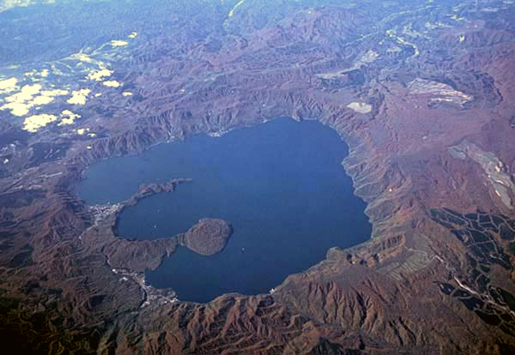The 11-km-wide Towada caldera, seen here from the E, formed during as many as six major explosive eruptions over a 40,000-year period ending about 13,000 years ago. The two peninsulas extending into the large caldera lake are the rims of Nakanoumi caldera, formed by collapse of the Goshikiiwa cone in the SSE section of the caldera. The rounded lava dome that was constructed at the tip of lower peninsula is Ogurayama, the source of the 915 CE eruption. Copyrighted photo by Yoshihiro Ishizuka (Japanese Quaternary Volcanoes database, RIODB, http://riodb02.ibase.aist.go.jp/strata/VOL_JP/EN/index.htm and Geol Surv Japan, AIST, http://www.gsj.jp/).