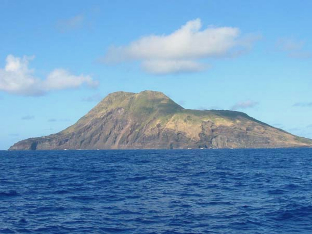 The 3-km-wide Sarigan volcano is seen here from the E during a 2003 NOAA expedition to the Marianas Islands.The cone has a 750-m-wide summit crater that forms the flat area to the right and it contains a small cone. More recent eruptions produced two lava domes from vents on and near the S crater rim, forming the island's high point at the left part of the summit. Holocene lava flows from the dome complex formed the peninsula to the far left. Image courtesy of NOAA, 2003 (http://oceanexplorer.noaa.gov/explorations/03fire/).