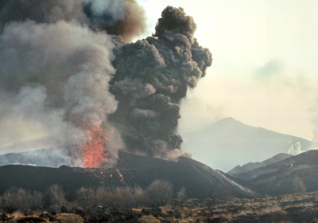 A major eruption took place from fissure vents on the N and S flanks of Italy's Etna volcano beginning on 26 October 2002. Lava flows cut across roads, and several hotels, restaurants, a ski school, ski lift pylons, and power lines were destroyed. This photo, taken on the 28th, looks towards the summit from the lower NE rift zone and shows lava fountaining and an ash plume from the two upper vents as well as small white plumes from the upper part of the eruptive fissure (far middle right). Photo by Jean-Claude Tanguy, 2002 (University of Paris).