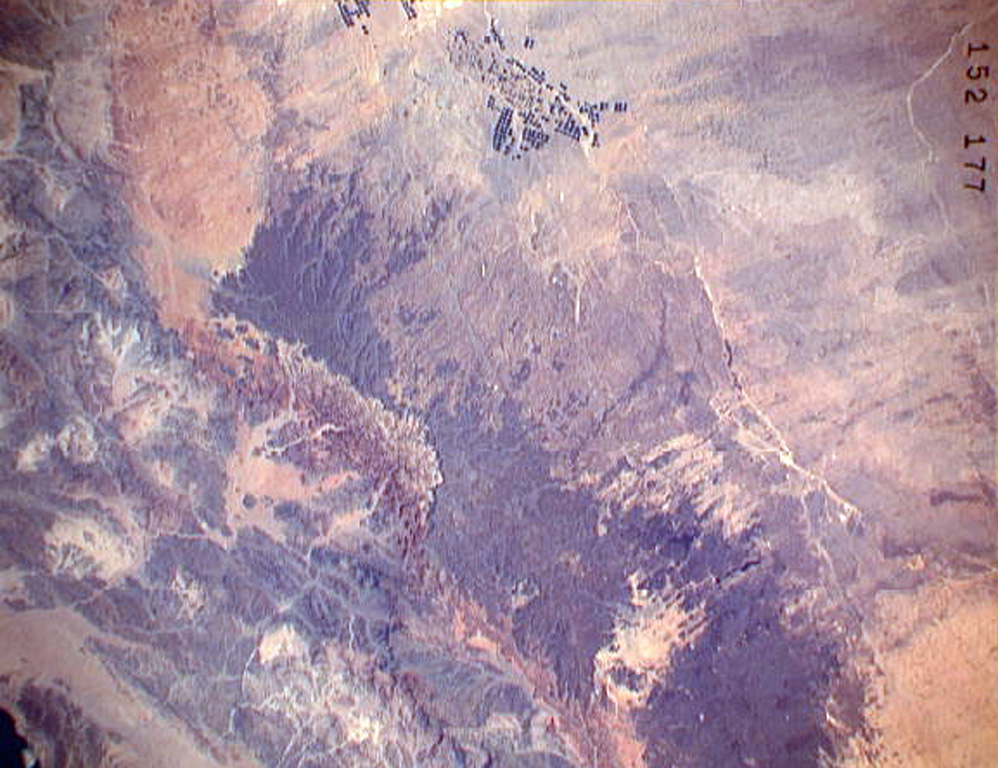 The darker-colored area extending diagonally down the center of this Space Shuttle image is Harrat ar Rahah, the northernmost of a series of Quaternary volcanic fields paralleling the Red Sea coast of Saudi Arabia. The geometrical outlines of the historical town of Tabuk (top center), located on the road leading from Hijr to Damascus, can be seen to the N. There are fewer young volcanoes in Harrat ar Rahah than in other harrats (lava fields) to the S. NASA Space Shuttle image STS37-152-177, 1991 (http://eol.jsc.nasa.gov/).