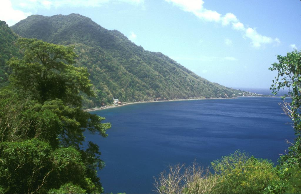 The Crabier lava dome rises about 500 m above the western shores of Soufrière Bay, with Scotts Head village at the far right. The dome is one of the youngest post-caldera features of the Morne Plat Pays volcanic complex.  The Galion thermal area lies in the saddle (upper left) between Crabier and the Morne Patates lava dome. Photo by Lee Siebert, 2002 (Smithsonian Institution).