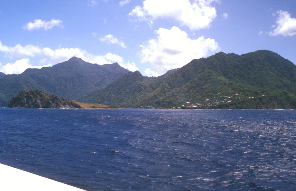 Scotts Head lava dome (left foreground) forms a narrow peninsula extending from the village of Scotts Head (right) on the southern tip of Dominica.  A submarine lava dome, named Mountain Top, is thought to be less than 9000 years old and rises to within 30 m of the sea surface about a kilometer south of Scotts Head dome.  The peak on the left horizon is Morne Play Pays stratovolcano; the post-caldera lava domes of Morne Patates, Crabier, and Morne Rouge form the center-to-right horizon.  Photo by Lee Siebert, 2002 (Smithsonian Institution).