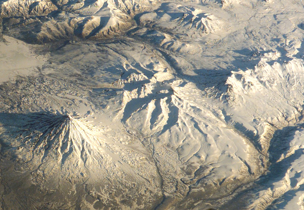 The glacially eroded edifice in this center of this International Space Station image is the mid- to late-Pleistocene age Schmidt volcano (north is to the upper right). Holocene monogenetic scoria cones are on the E and NE flanks. Kronotsky is to the lower left and the Gamchen complex to the far right. NASA International Space Station image ISS004-E-13788, 2002 (http://eol.jsc.nasa.gov/).