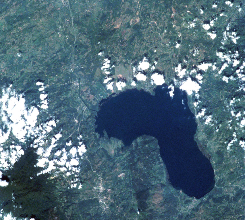 The Lake Yojoa volcanic field forms the entire northern shore of the 10 x 12 km lake, the largest in Honduras, in this International Space Station image with north to the upper left.  Cretaceous limestones lie west of the lake, and Tertiary volcanic rocks to the east.  Vents of the volcanic field, which extends to the top of the image, are concentrated along two NW- and NE-trending lines.  The Lake Yojoa volcanic field has produced both tholeiitic and alkaline basaltic rocks. NASA International Space Station image ISS001-350-18, 2001 (http://eol.jsc.nasa.gov/).