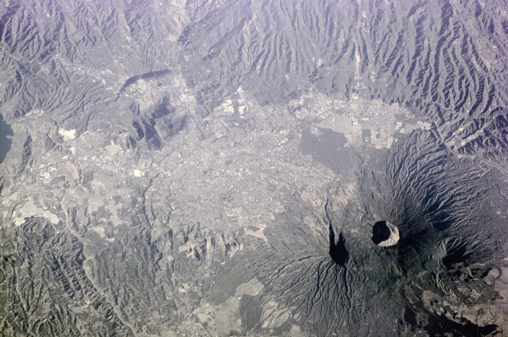 The capital city of San Salvador extends across much of this photo taken from the International Space Station (with north to the bottom) and encroaches on the flanks of San Salvador volcano. The Boquerón crater is 1.5 km wide and lies within a late-Pleistocene crater whose eastern wall is shown by the shadow to the left. The dark area to the bottom right is a flank lava flow produced during the 1917 eruption. NASA International Space Station image ISS001-E-5903, 2001 (http://eol.jsc.nasa.gov/).