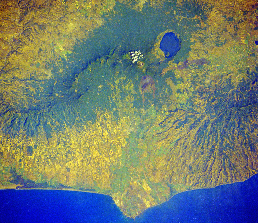 Four volcanoes in western El Salvador are visible in this Space Shuttle image.  The forested ridge at the left-center is the Apaneca Range, a complex of calderas and small stratovolcanoes.  The summit crater of Santa Ana volcano lies below the small cloud bank, and the brownish area below it is Izalco volcano.  A circular lake partially fills Coatepeque caldera.  The Acajutla Peninsula at the bottom, named after the port city of Acajutla, was formed by a massive debris avalanche produced by the late-Pleistocene collapse of Santa Ana volcano. NASA Space Shuttle image STS61C-31-45, 1986 (http://eol.jsc.nasa.gov/).