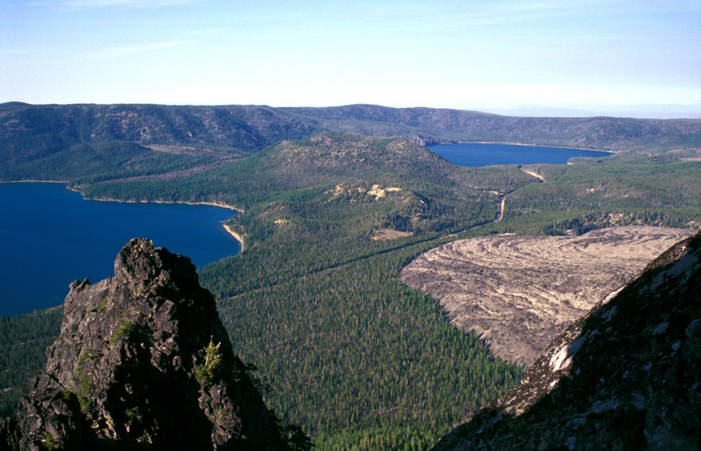 Newberry volcano, one of the largest Quaternary volcanoes in the conterminous United States, lies 60 km E of the crest of the Cascade Range in central Oregon. The shield volcano contains a 5 x 7 km caldera with two lakes, Paulina Lake (left) and East Lake (right). Newberry has been active during the Holocene at vents within the caldera that have produced pumice cones and obsidian lava flows (like Obsidian flow to the lower right), and outside the caldera forming scoria cones on its broad flanks. Photo by Lee Siebert, 2002 (Smithsonian Institution).
