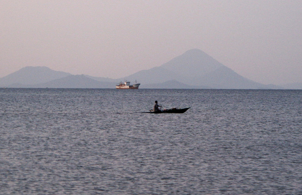 Conical Bola volcano (also known as Wangore) rises to the NW across Stetin Bay. The symmetrical stratovolcano is located immediately SW of Dakatau caldera and forms the high point of the Willaumez Peninsula in central New Britain. The forested cone has a well-preserved, 400-m-wide crater. No historical eruptions have been documented from Bola, but its morphology suggests very recent activity. Photo by Elliot Endo, 2002 (U.S. Geological Survey).