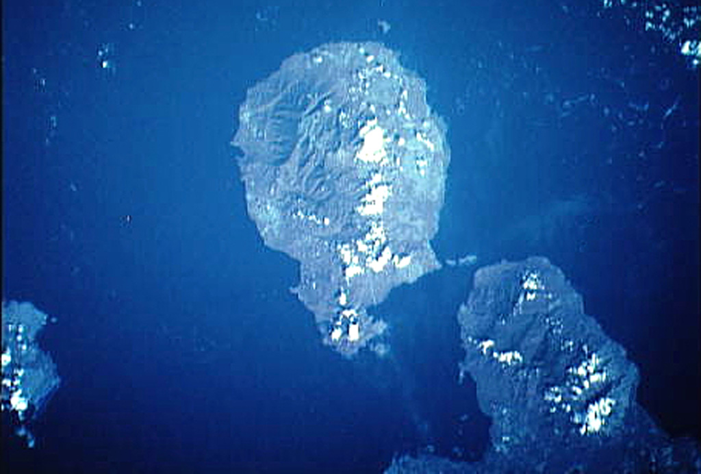 Goodenough (center) is the roughly circular volcanic island that is the westernmost of the D'Entrecasteaux Islands in this NASA satellite image with north to the upper right. Several Holocene eruptive centers that may be only a few hundred years old are located around the margins of fault-bounded metamorphic rocks that form the central part of Goodenough Island. The youngest volcanic features, which include the Walilagi Cones, are located at the SE end of the island on the Bwaido Peninsula (lower center). NASA Space Shuttle image STS44-83-79, 1991 (http://eol.jsc.nasa.gov/).