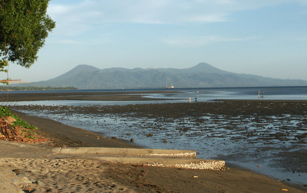 The Krummel-Garbuna-Welcker volcanic complex at the S end of the Willaumez Peninsula, across Stetin Bay. The complex consists of three volcanic peaks, Krummel, Garbuna, and Welcker, along a N-S line. The most prominent peaks, Welcker (right) and Krummel (left), form the N and S sides of the complex, respectively. The lower peaks of the centrally located Garbuna contain a large unvegetated area with an extensive thermal field. Photo by Elliot Endo, 2002 (U.S. Geological Survey).