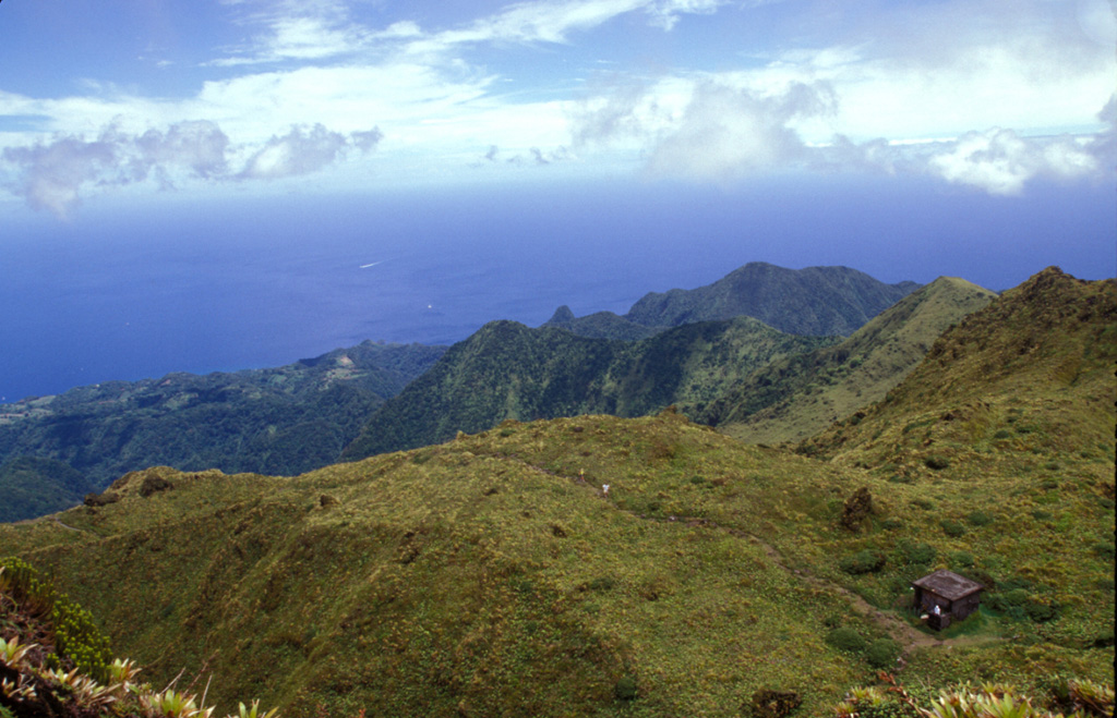 This view looks west from the 1902 lava dome within the summit crater of Mount Pelée.  The area beyond the grassy knoll was part of the first portion of the ancestral volcano that underwent massive edifice collapse more than 100,000 years ago.  This massive collapse produced a 25 cu km debris avalanche that swept into the Caribbean Sea up to 70 km from the coastline.  Mount Pelée was subject to three major episodes of edifice collapse--the second took place about 25,000 years and the third about 9000 years ago.   Photo by Paul Kimberly, 2002 (Smithsonian Institution).