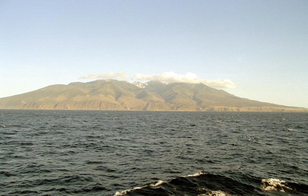 Berutarubesan volcano forms the SW tip of Iturup Island, seen here from the SE. Glacial valleys descend the flanks and a low saddle on the NE side (far right) separates Berutarubesan from the slopes of Moekeshiwan caldera. Light-colored geothermal areas can be seen in the summit crater on the center horizon. Photo by Alexander Rybin, 2001 (Institute of Marine Geology and Geophysics, Yuzhno-Sakhalin).
