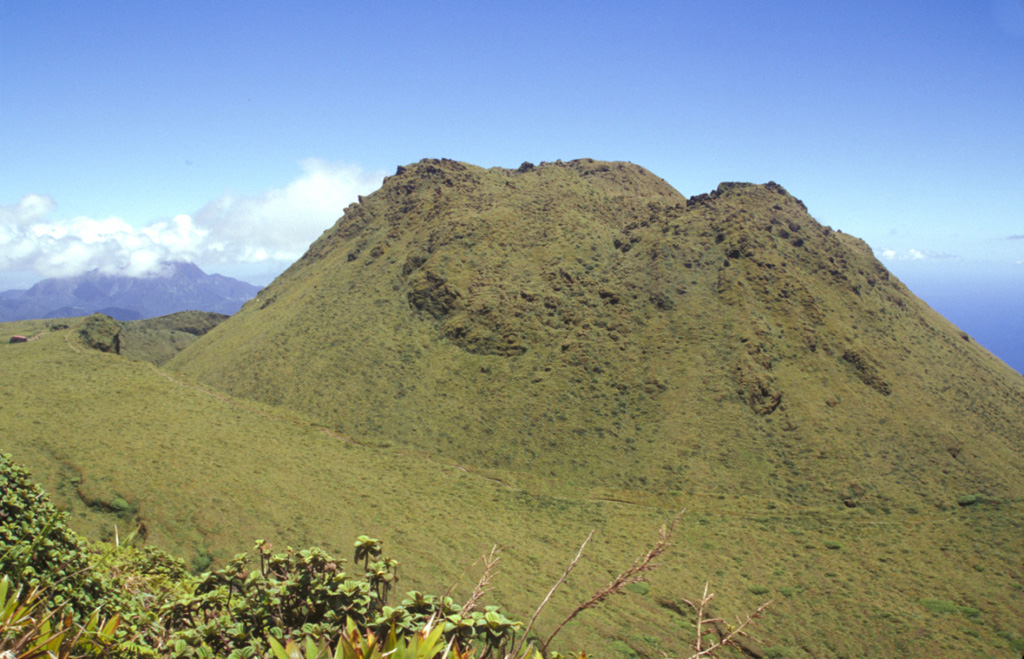 The 1902 lava dome fills much of the l'Etang Sec summit crater, as seen here from Morne Macouba, north of the summit.  Following the catastrophic eruption on May 8, 1902, rapid growth of a summit lava dome began; it reached 350 m height by July 6.  Intermittent explosive activity continued until October 31, 1903 and lava dome growth continued on a diminishing scale until October 5, 1905.  The famous spine at one point rose to 1617 m, 220 m above the current summit (the 1929 lava dome), before it crumbled away. Photo by Paul Kimberly, 2002 (Smithsonian Institution).
