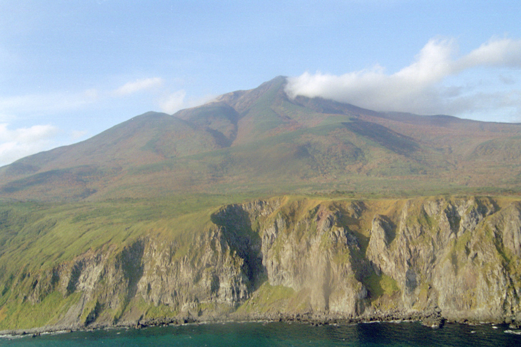 The SE slopes of Sashiusudake tower above steep sea cliffs along the Pacific Ocean coast of Iturup Island. Lava flows descended 4-5 km SE to reach the ocean along a broad front N of where this photo was taken. An eruption in 1951 consisted of weak explosive activity at the summit. Geothermal activity continues from the summit and flank craters, and the SW-flank geothermal field contains hot springs and geysers. Photo by Alexander Rybin, 1999 (Institute of Marine Geology and Geophysics, Yuzhno-Sakhalin).