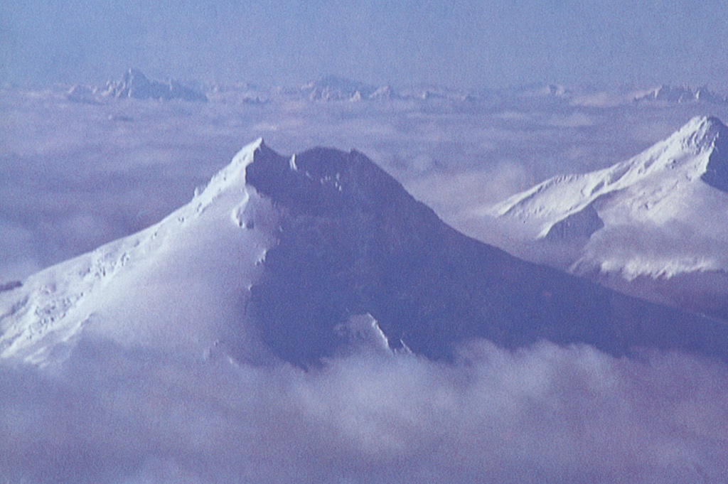 Snow-mantled Volcán Maca, the highest volcano between Lanín and Lautaro, rises to 2960 m NW of Puerto Aisén.  This glacier-covered, basaltic-to-andesitic stratovolcano lies within a caldera and contains a summit lava dome.  Five flank cinder cones and lava domes lie along a NE-trending fissure that extends 15 km from the summit.  The volcano lies along the regional Liquiñe-Ofqui fault zone.  Volcan Cay (far right) lies to the NE of Maca. Photo by Oscar González-Ferrán (University of Chile).