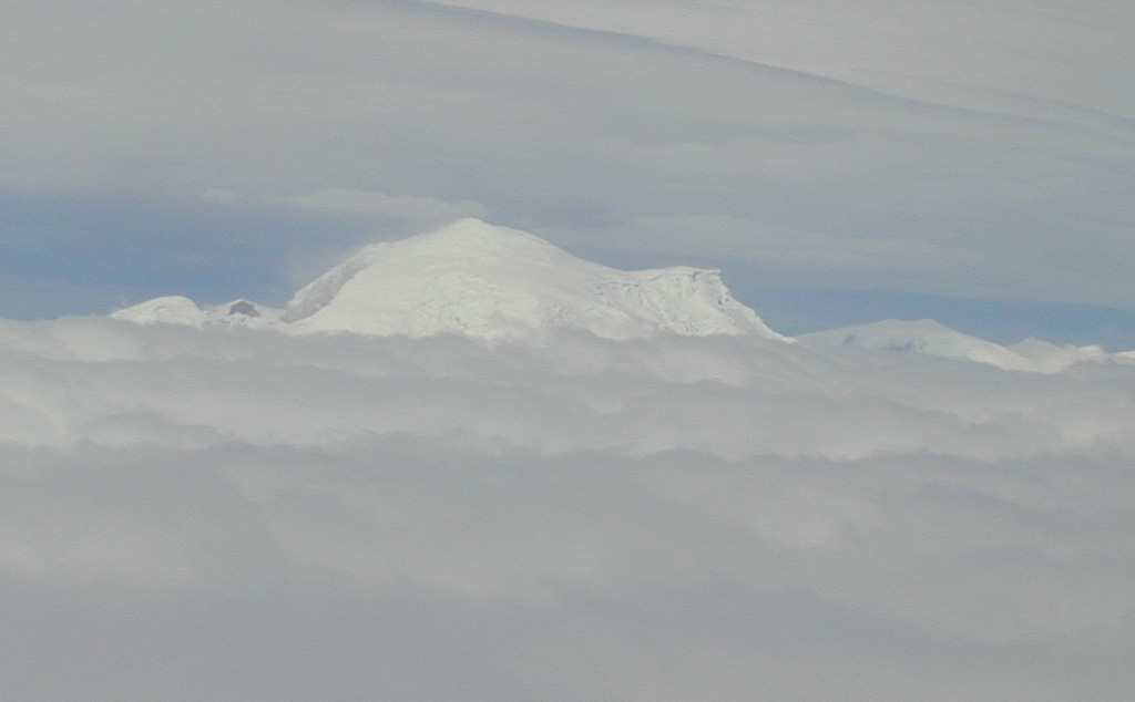 The northern side of Lautaro volcano rises above a sea of clouds.  A 300-km gap occurs between Cerro Hudson and Lautaro, the northernmost of five volcanoes comprising the australandean volcanic zone of the southernmost Chilean Andes.   Glacier-covered, 3607-m-high Lautaro volcano, the highest Chilean volcano below 40 degrees south, has a crater just below its summit on the NW side, and a 1-km-wide crater is located on the NE flank.   Photo by José Naranjo, 2002 (Servico Nacional de Geologica y Mineria).