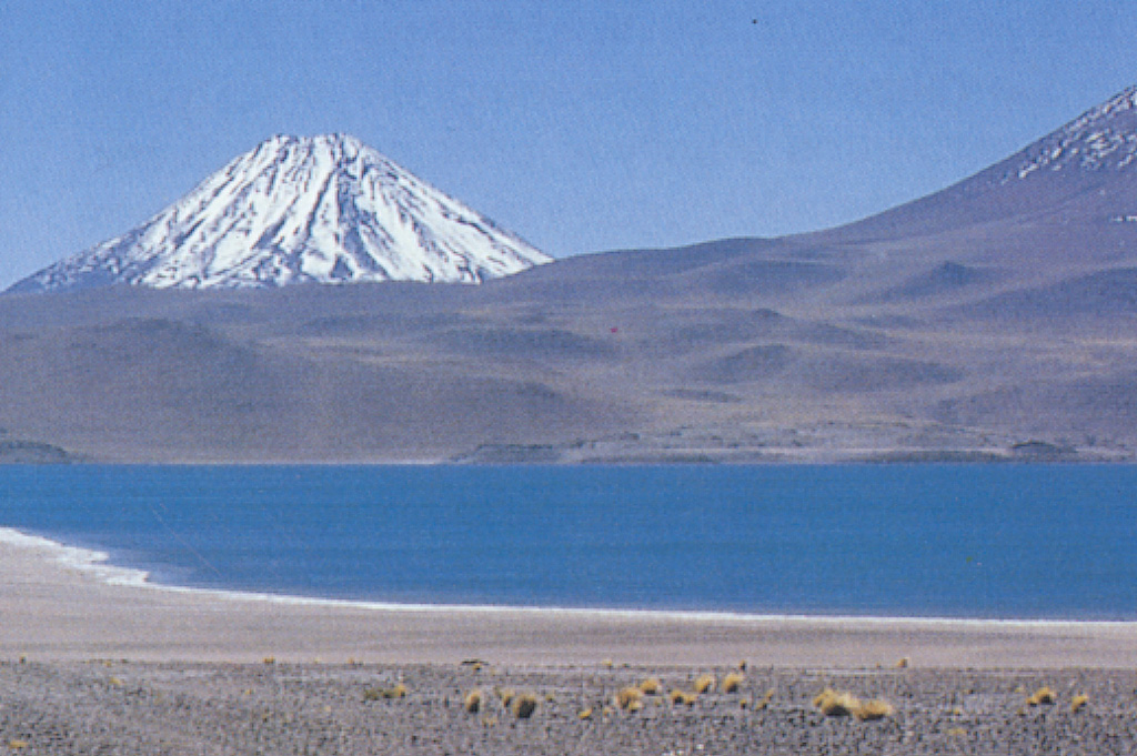 Snow-capped Volcán Chiliques is a conical stratovolcano located NNE of Laguna Miscanti (foreground).  The 5778-m-high summit of the volcano contains a 500-m-wide crater.  Several youthful lava flows, some of which are considered to be of Holocene age descend its flanks.  Chiliques had previously been considered to be dormant; however, in 2002 a NASA nighttime thermal infrared satellite image showed low-level hot spots in the summit crater and upper flanks.   Photo by Carlos Felipe Ramírez (courtesy of Oscar González-Ferrán, University of Chile).