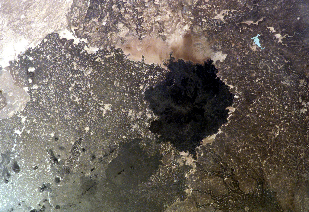 The dark-colored lava flows in this NASA International Space Station image (N to the left) lie at the south end of the Es Safa volcanic field. This basaltic field (also referred to as As Safa), lies SE of the capital city of Damascas (Dimashq) and contains at least 38 scoria cones. This volcanic field lies within the northern part of the massive alkaline Harrat Ash Shaam volcanic field that extends from southern Syria to Saudi Arabia. NASA International Space Station image ISS007-E-8414, 2003 (http://eol.jsc.nasa.gov/).