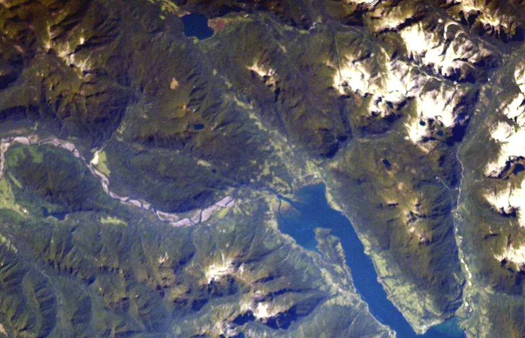The major regional N-S-trending Liquiñe-Ofqui fault extends along the Estuario Reloncaví (lower right) through Ralún Bay (center) to Lake Cayutúe (just left of the top of the image).  About 20 basaltic cinder cones, maars, and lava flows of the Cayutué-La Viguería volcanic field lie along this lineament.  La Viguería and Volcán Cayutué are the principal cones.  The former temporarily dammed the Río Petrohué, the meandering stream at the left. NASA International Space Station image ISS006-E-42993, 2003 (http://eol.jsc.nasa.gov/).