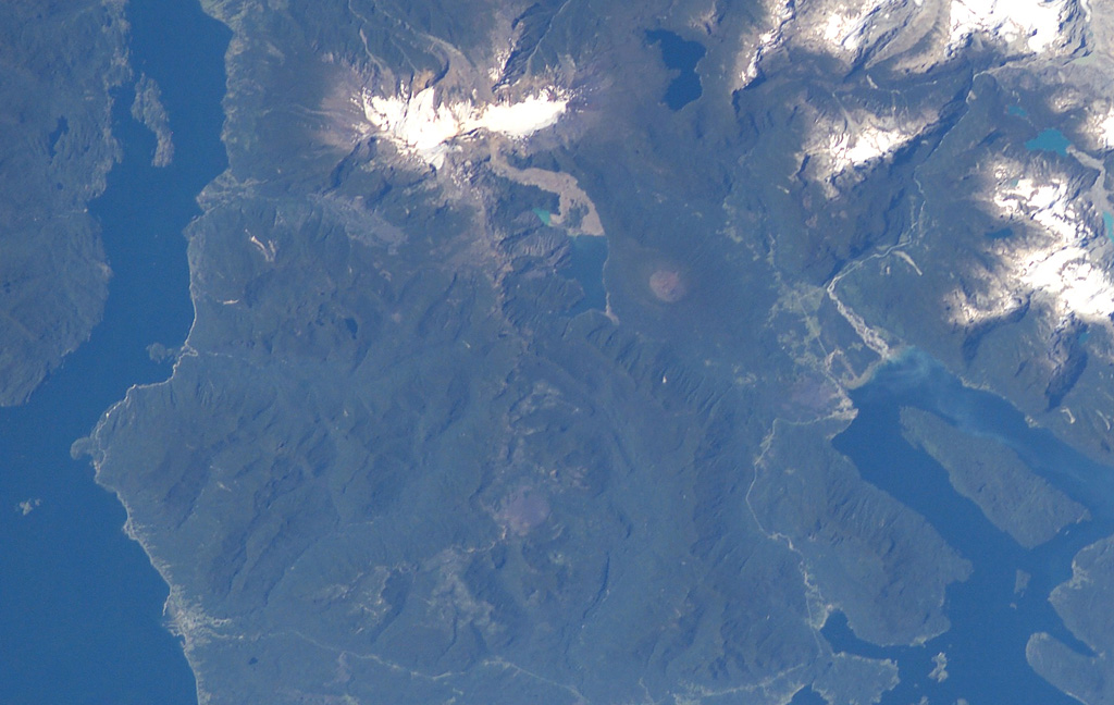 The forested volcanic complex in the lower center of this NASA Space Station image (with north to the left) is Hualique (also known as Apagado).  This stratovolcano is located SW of snow-covered Yate volcano (top; left of center) and occupies the peninsula between the Gulf of Ancud and the Reloncaví estuary (upper left).  A 6-km-wide caldera is open to the SW.  Hornopirén volcano is the small rounded brownish peak below and to the right of Yate volcano. NASA International Space Station image ISS006-E-42995, 2003 (http://eol.jsc.nasa.gov/).